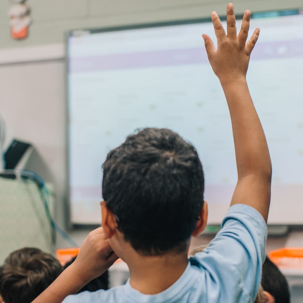 Student raising a hand in class to request a hall pass